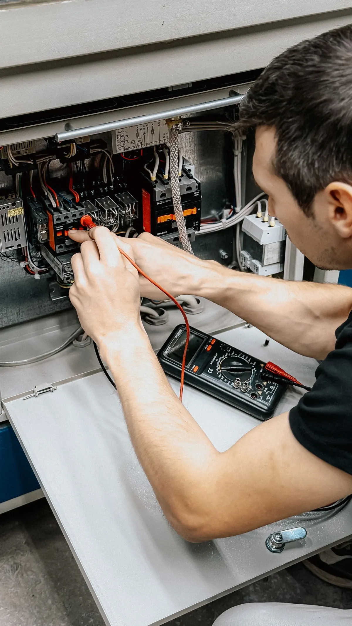 Elettricista che controlla con un multimetro un quadro elettrico aperto