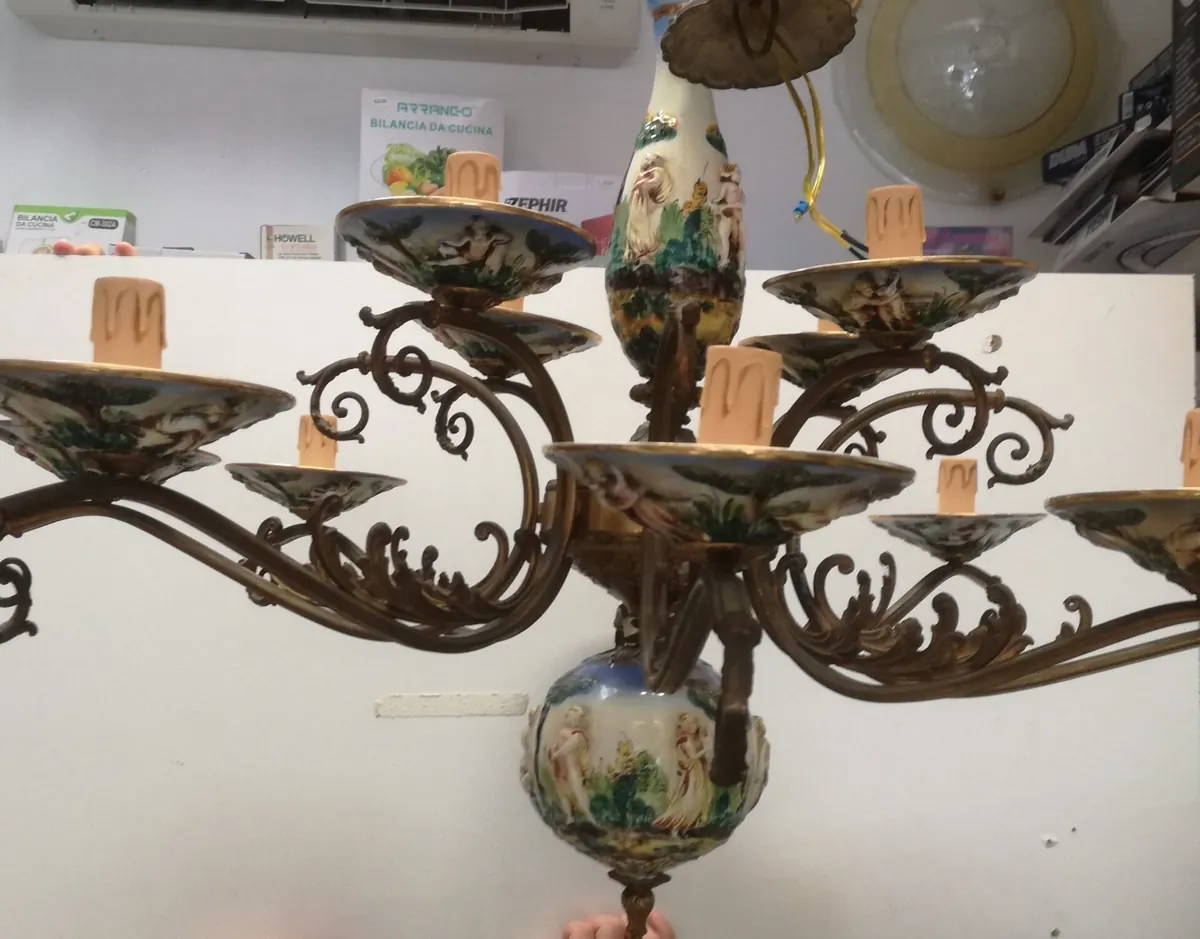 Lampadario antico in bronzo e ceramica dipinta con motivi in rilievo, fotografato in negozio