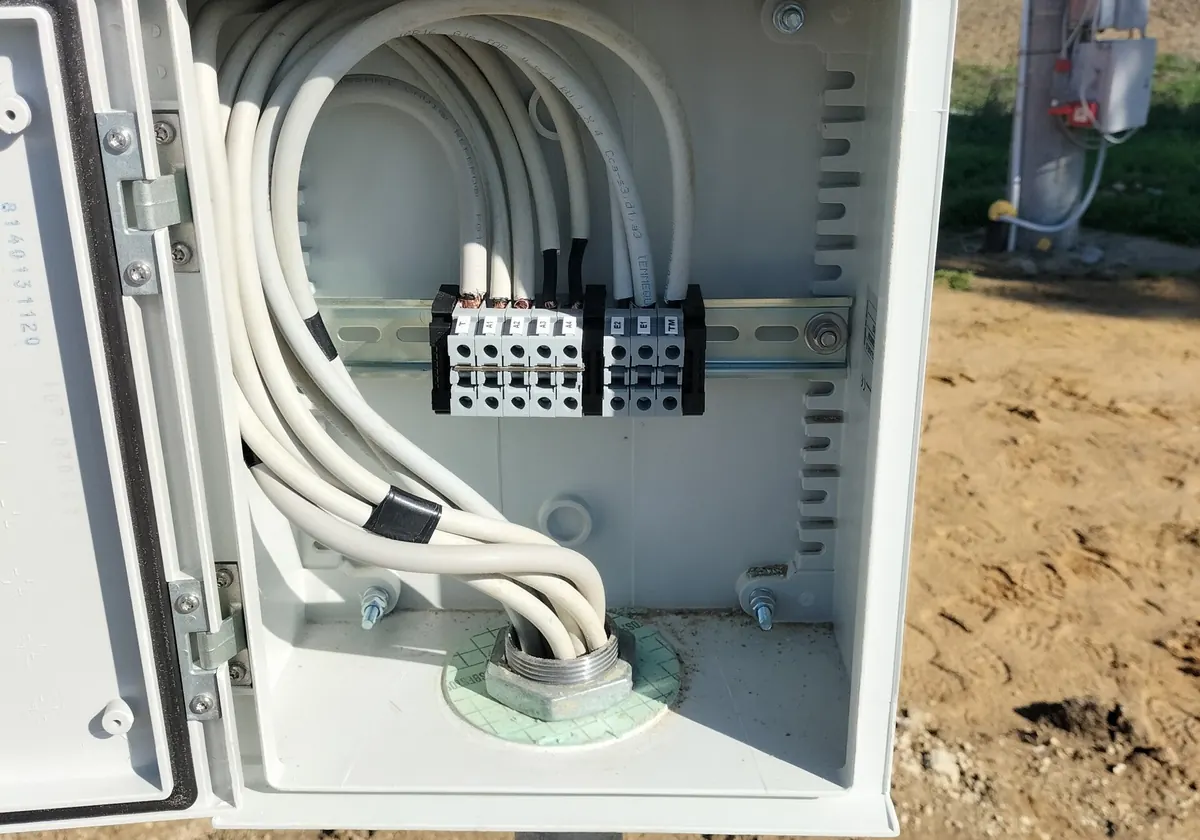 Quadro aperto in cantiere: cavi bianchi ordinati che arrivano a una morsettiera con le sigle T, A1, A2, A3, A4, E1, E2 e TM