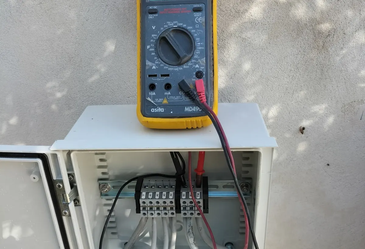 Multimetro appoggiato su un quadro aperto con morsettiera, durante la verifica dell’impianto